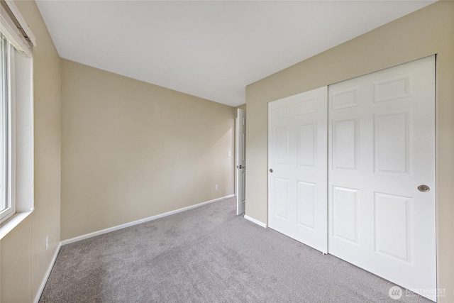 unfurnished bedroom featuring a closet, baseboards, and carpet