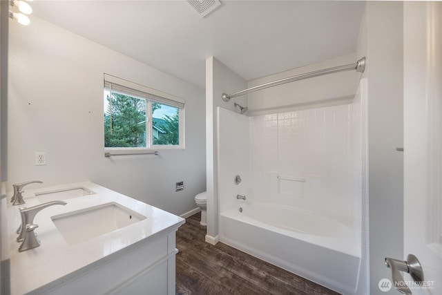 full bath featuring toilet, wood finished floors, visible vents, and a sink