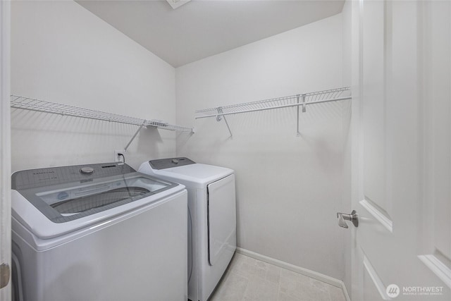 laundry room with laundry area, washing machine and dryer, and baseboards