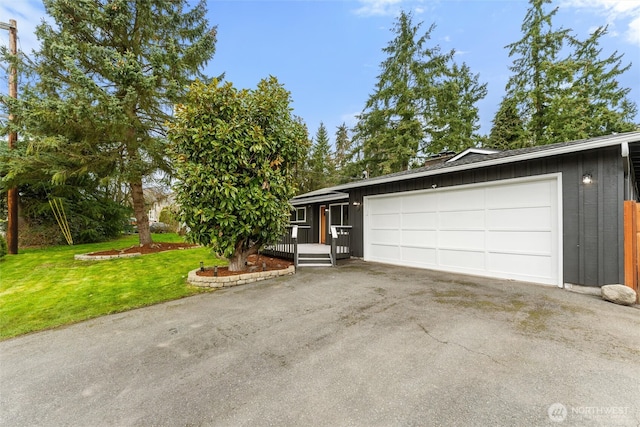 view of front facade with aphalt driveway, a garage, and a front yard