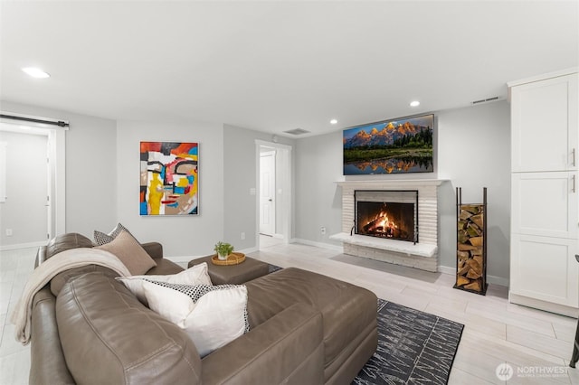 living room featuring visible vents, recessed lighting, a brick fireplace, and baseboards