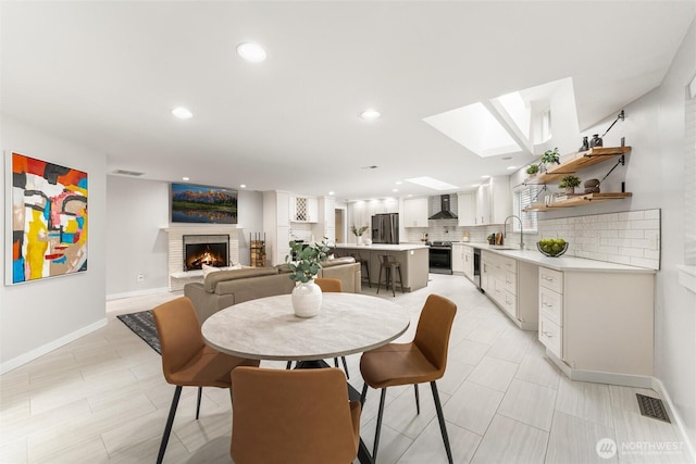 dining room with visible vents, recessed lighting, a skylight, a fireplace, and baseboards