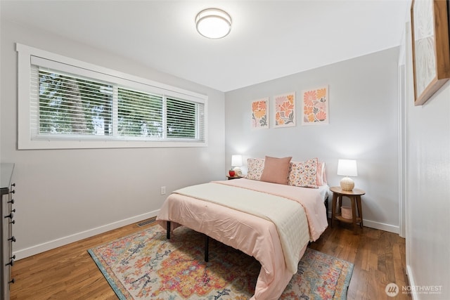 bedroom featuring visible vents, baseboards, and wood finished floors