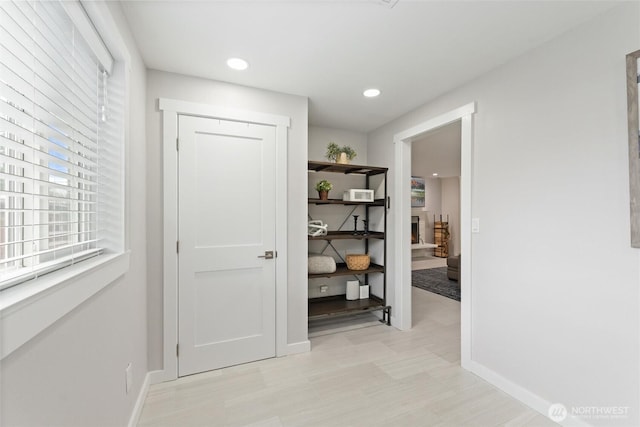 hallway with recessed lighting, baseboards, and light floors