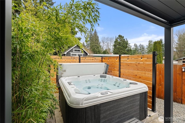 view of patio with a hot tub and fence