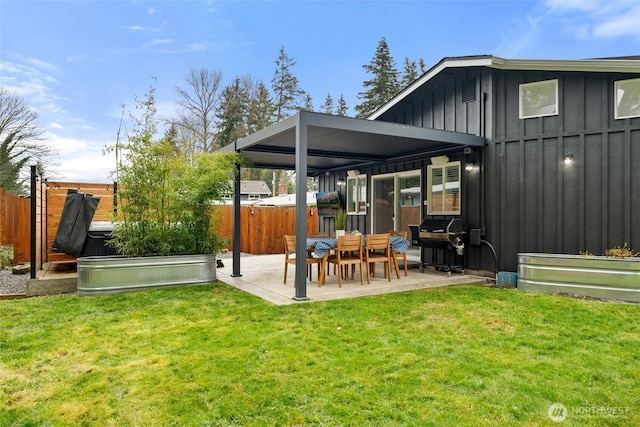 rear view of house with a patio area, a yard, fence, and board and batten siding