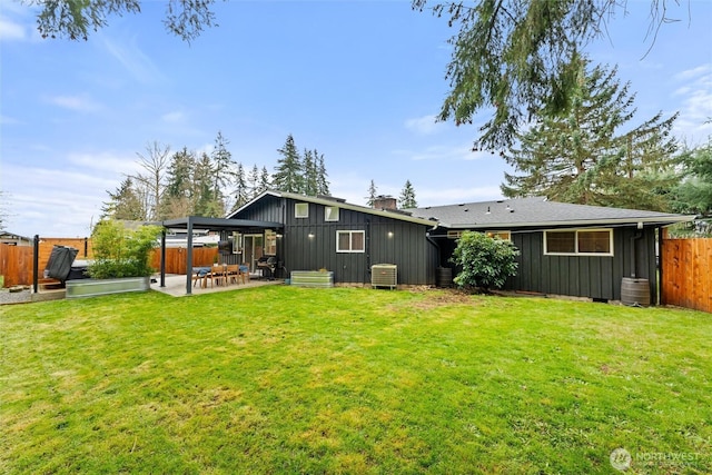 back of property with a lawn, a patio, a fenced backyard, board and batten siding, and a chimney