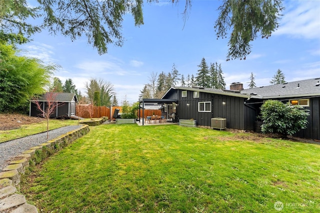 view of yard featuring an outbuilding, fence, a shed, and a patio area