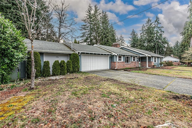 single story home featuring a front lawn, driveway, a garage, brick siding, and a chimney