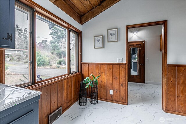 kitchen featuring a wainscoted wall, wooden walls, visible vents, and marble finish floor