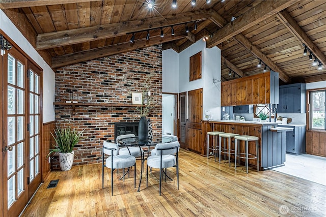 kitchen with light wood-type flooring, visible vents, beam ceiling, and wooden ceiling