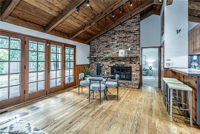 living room with beamed ceiling, wainscoting, wooden ceiling, a fireplace, and hardwood / wood-style flooring