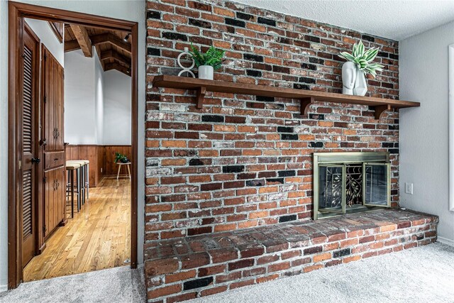 room details with a brick fireplace, a wainscoted wall, carpet floors, and a textured ceiling