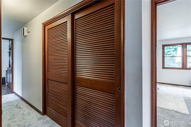 corridor with baseboards and carpet floors