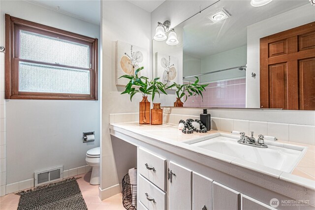 full bath featuring visible vents, baseboards, toilet, vanity, and a shower