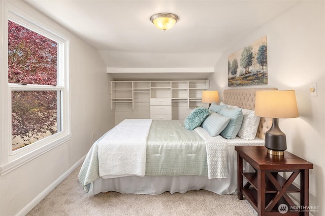 carpeted bedroom with lofted ceiling, multiple windows, and baseboards