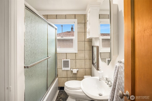 full bath with a sink, tile walls, shower / bath combination with glass door, and marble finish floor