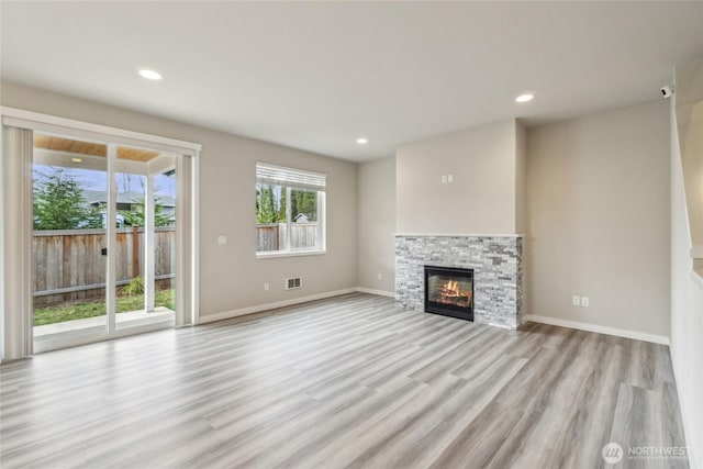 unfurnished living room featuring visible vents, a fireplace, light wood-type flooring, and baseboards