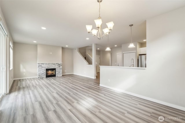 unfurnished living room with recessed lighting, baseboards, light wood finished floors, and a sink