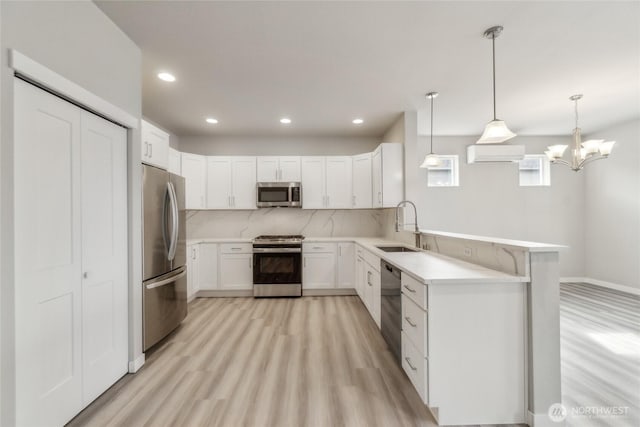 kitchen featuring backsplash, an AC wall unit, a peninsula, stainless steel appliances, and a sink