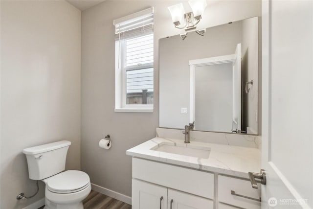 bathroom with toilet, wood finished floors, an inviting chandelier, baseboards, and vanity