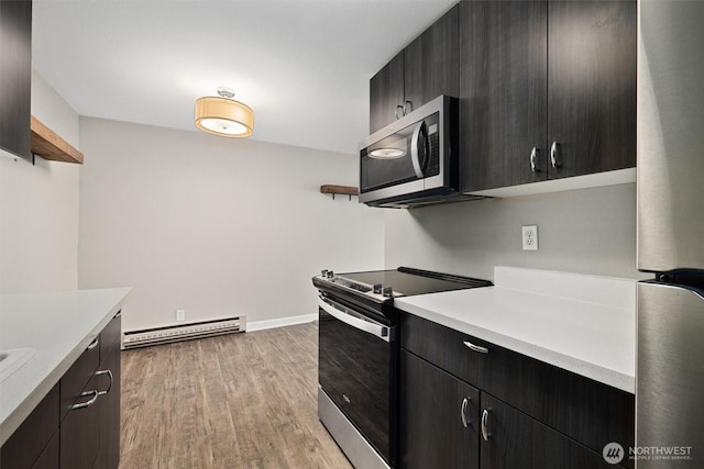 kitchen with light wood finished floors, a baseboard heating unit, light countertops, appliances with stainless steel finishes, and open shelves