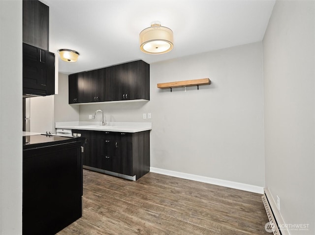 kitchen with dark cabinetry, baseboards, dark wood finished floors, freestanding refrigerator, and a sink