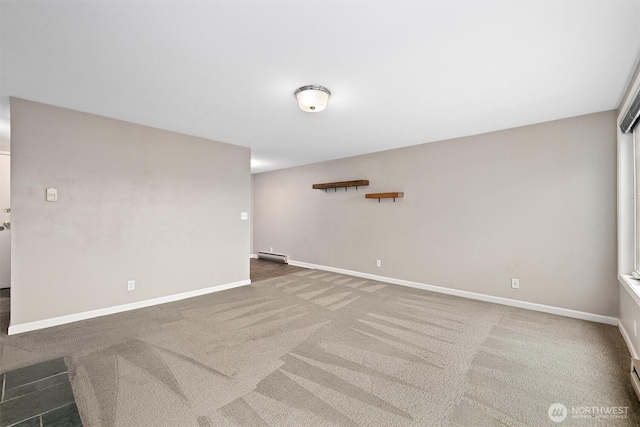 spare room featuring a baseboard heating unit, baseboards, and carpet flooring