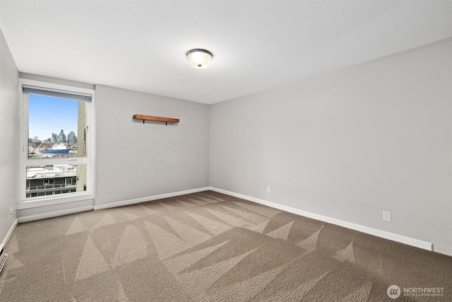 carpeted empty room featuring baseboards