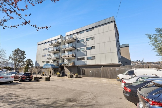 view of building exterior with fence and uncovered parking