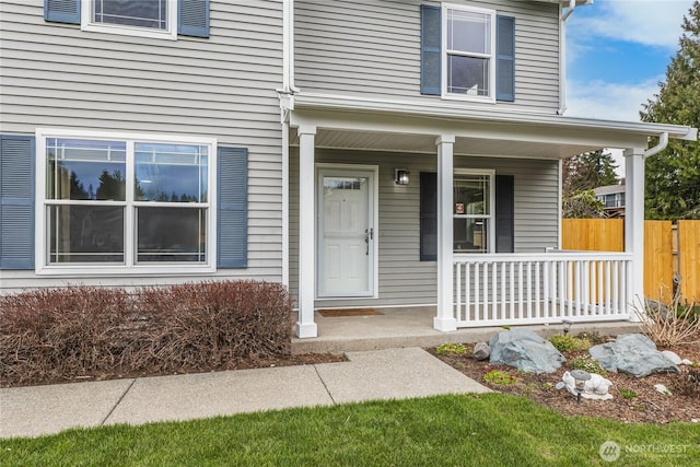 entrance to property with a porch and fence