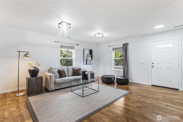 living area featuring visible vents, wood finished floors, and baseboards