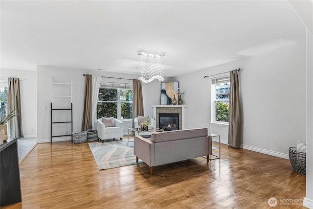 living area with a tiled fireplace, plenty of natural light, and light wood-type flooring