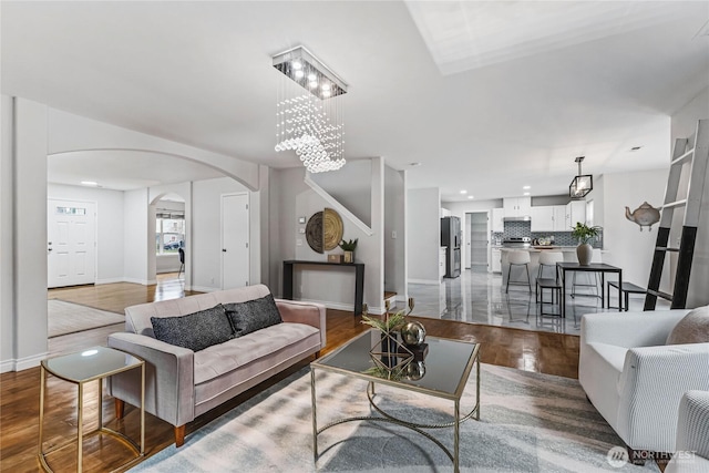 living area featuring recessed lighting, baseboards, arched walkways, and wood finished floors