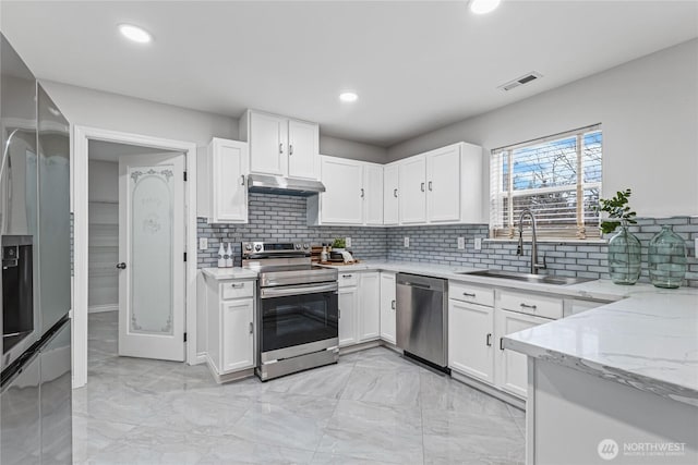 kitchen featuring light stone counters, visible vents, a sink, stainless steel appliances, and under cabinet range hood