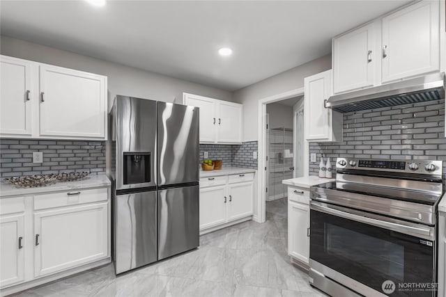 kitchen featuring under cabinet range hood, light countertops, appliances with stainless steel finishes, white cabinets, and marble finish floor