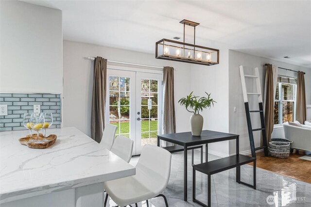 dining room featuring wood finished floors, a notable chandelier, french doors, and baseboards