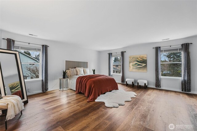 bedroom featuring visible vents, multiple windows, and wood finished floors