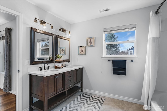 bathroom featuring double vanity, baseboards, visible vents, and a sink