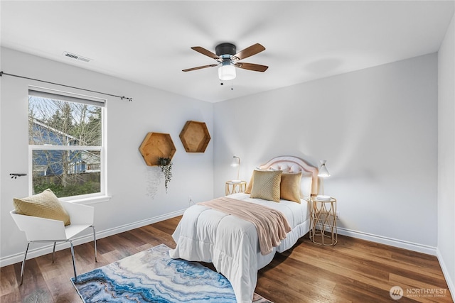 bedroom featuring visible vents, a ceiling fan, baseboards, and wood finished floors