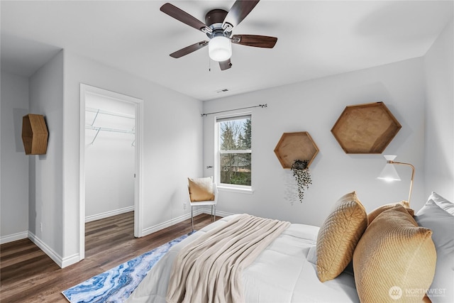 bedroom featuring a walk in closet, visible vents, wood finished floors, and baseboards