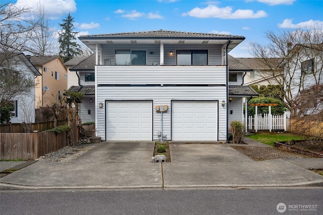 traditional home featuring a garage, concrete driveway, and fence