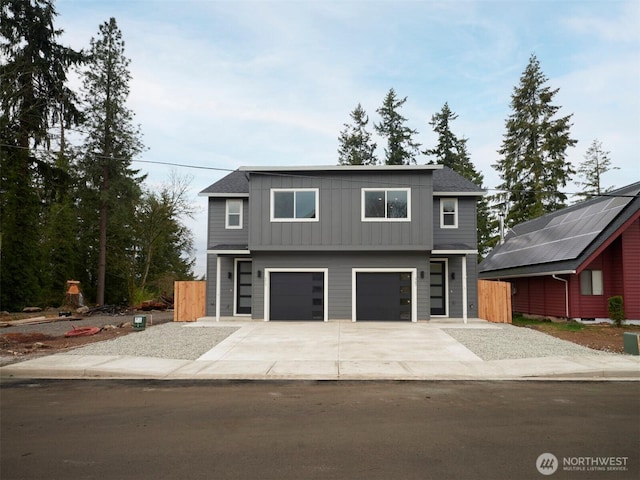 contemporary house with board and batten siding, concrete driveway, an attached garage, and fence