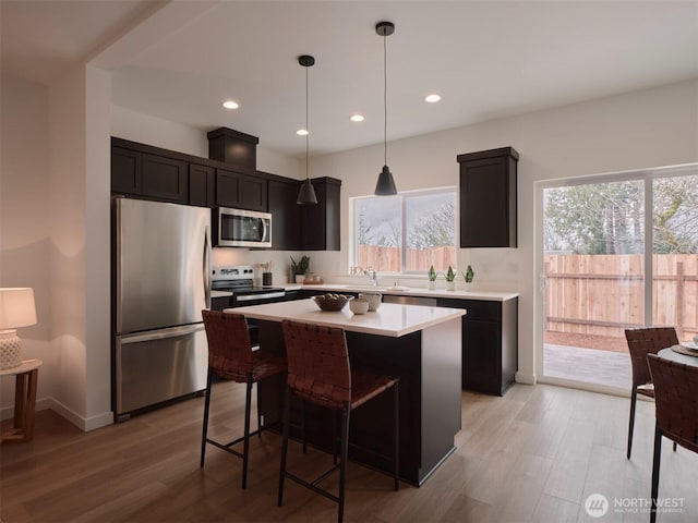 kitchen with a center island, stainless steel appliances, light countertops, and light wood-style floors