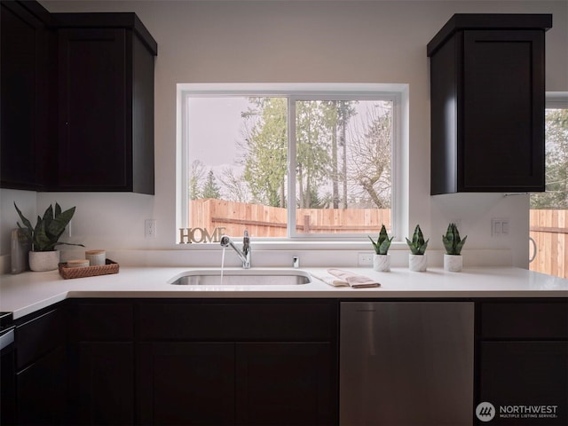 kitchen with fridge, dark cabinetry, light countertops, and a sink