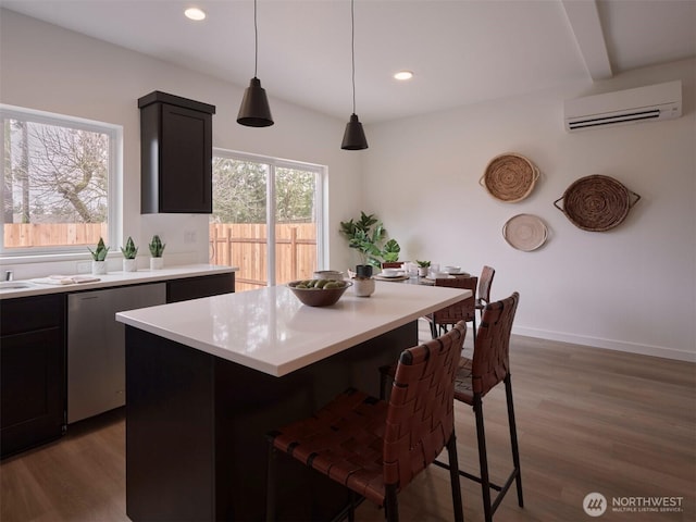 kitchen with dishwasher, an AC wall unit, a kitchen bar, light countertops, and dark wood-style flooring