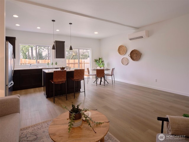 interior space featuring recessed lighting, light wood-type flooring, baseboards, and a wall mounted AC