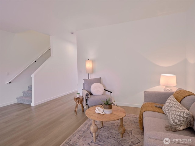 living room featuring stairs, baseboards, and wood finished floors