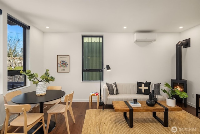 living room featuring recessed lighting, wood finished floors, a wood stove, and a wall mounted AC