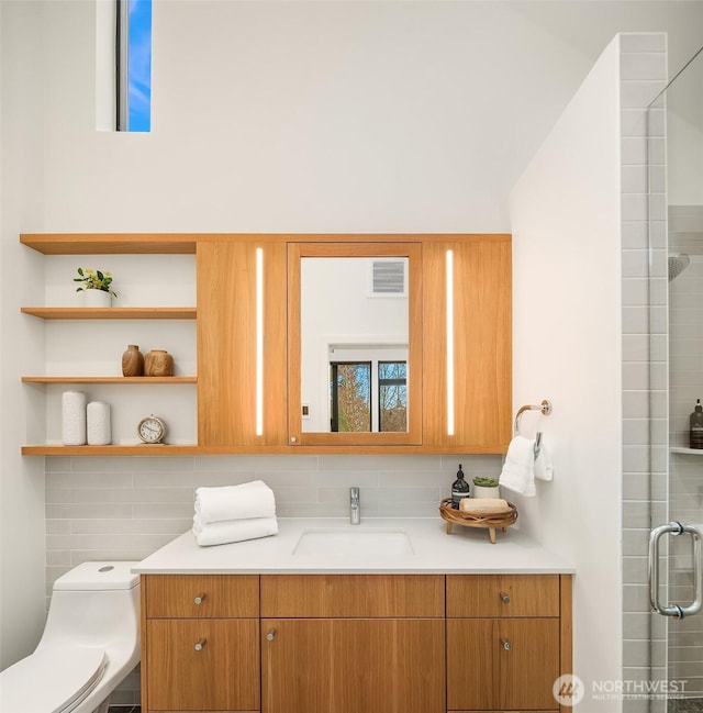 bathroom featuring vanity, visible vents, a tile shower, toilet, and backsplash